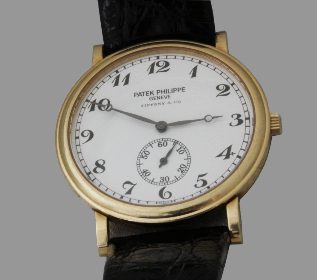 A classic Patek Philippe 18k yellow gold Calatrava wristwatch retailed by Tiffany & Co., circa 1980s. This has a round dial featuring Arabic numbers, subsidiary seconds, with manual-wind movement and the original buckle.