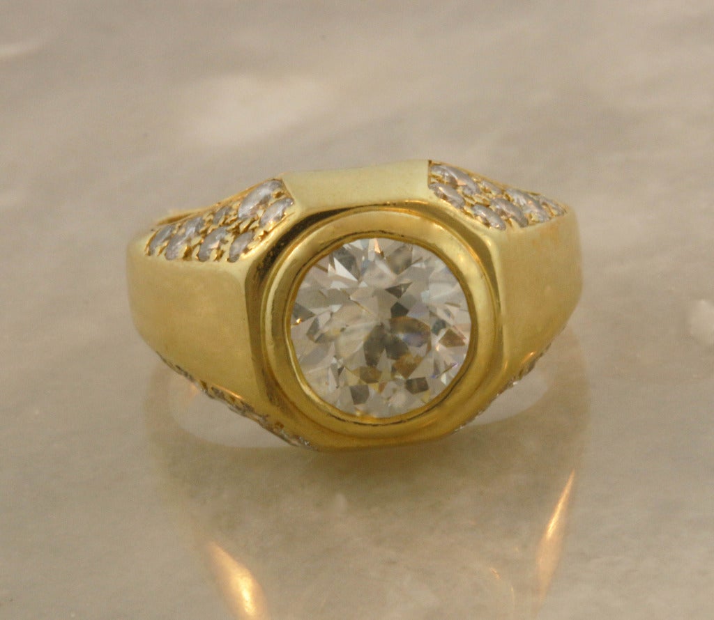 Beautiful BVLGARI 18K yellow gold ring with a bezel set diamond weighing approximately 2 carats. The center stone is accented by numerous diamonds set into the side of the mounting.