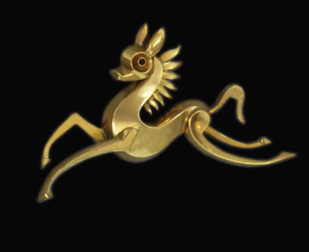 This brooch is a stunning example of 1940’s Parisian design. A stylized prancing horse of 18K gold features a sparkling ruby eye, whimsical ears and a sunburst-like mane, and exemplifies mid-century fashion at its most striking.