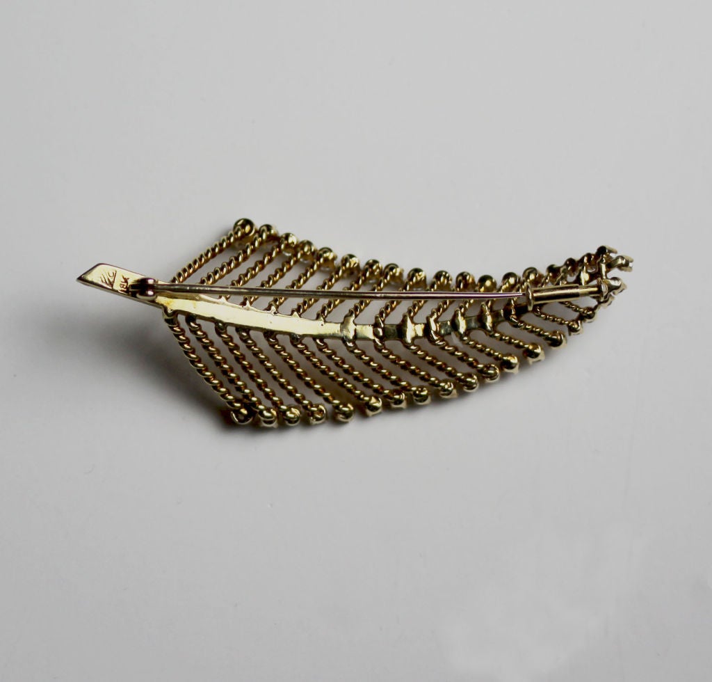Designed by Marianne Ostier, this 18K gold brooch epitomizes 1950’s retro glamour. The stylized leaf motif features a gold center stem from which radiate gold twisted rope veins that each end with a delicate round-cut diamond.
