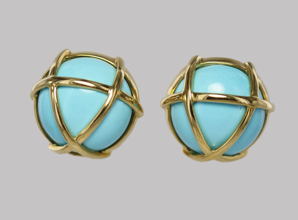 These classic 1990's ear-clips by Verdura are made of bright turquoise domes encased by 18k gold cages, with a clean and graphic silhouette.