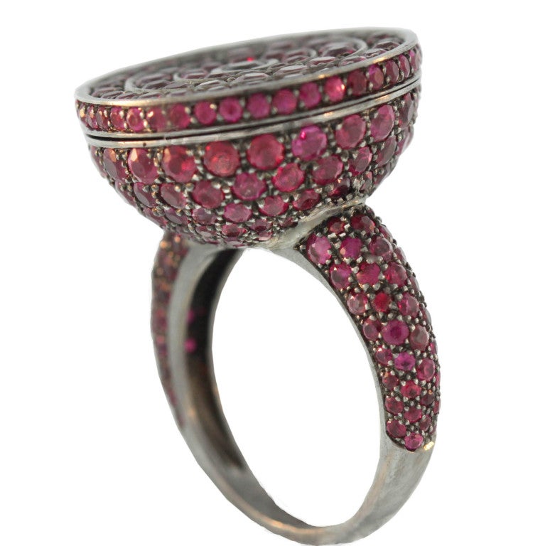 Made of blackened 18K gold and densely set with vivid red rubies, this Boucheron “poison” ring has a secret top that opens to reveal a small, hidden compartment. Numbered E03638.