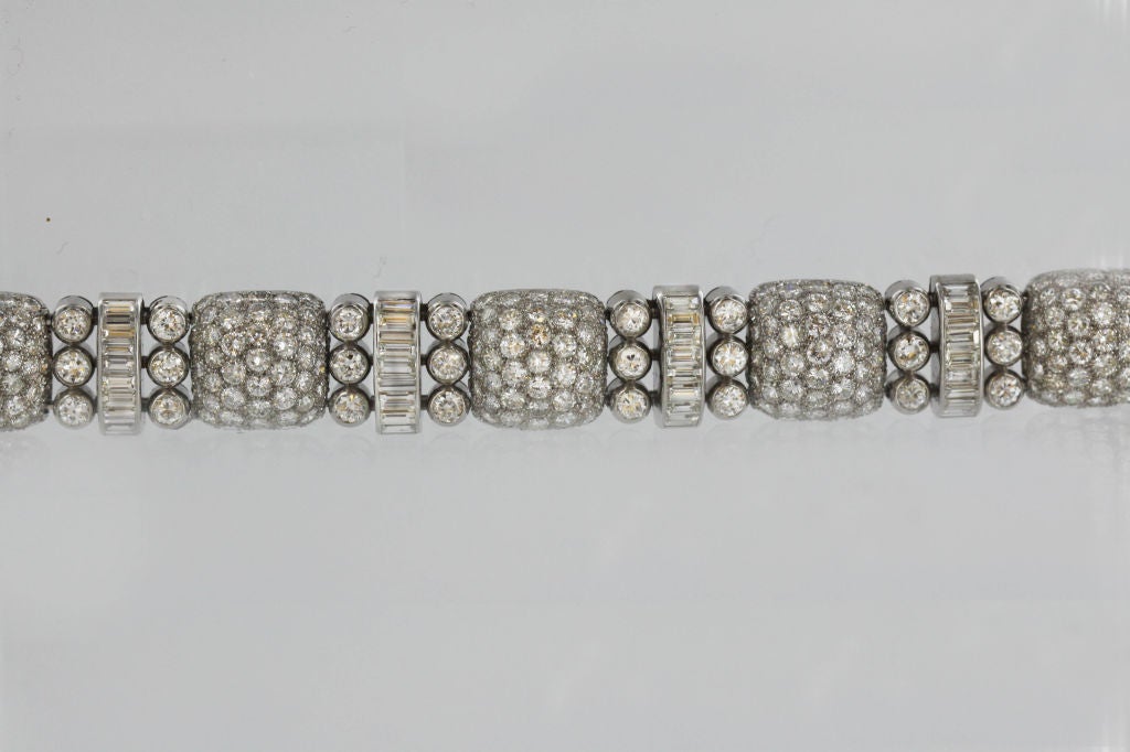 This classic 1940's platinum bracelet features a design of round-cornered squares, centrally set with approximately 31 carats of brilliant-cut diamonds. Flanking these stones are single rows of round-cut gems, and baguette-cut diamond spacers of