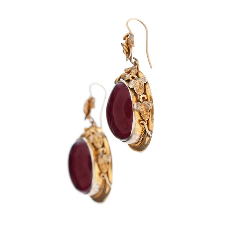 A finely crafted pair of garnet drop earrings handmade and all original from 1890. English made, the 15ct yellow gold metal is meticulously crafted in a splendid floral design. The cabochon garnets are 0.65 inches, the earrings measuring 1.6 inches