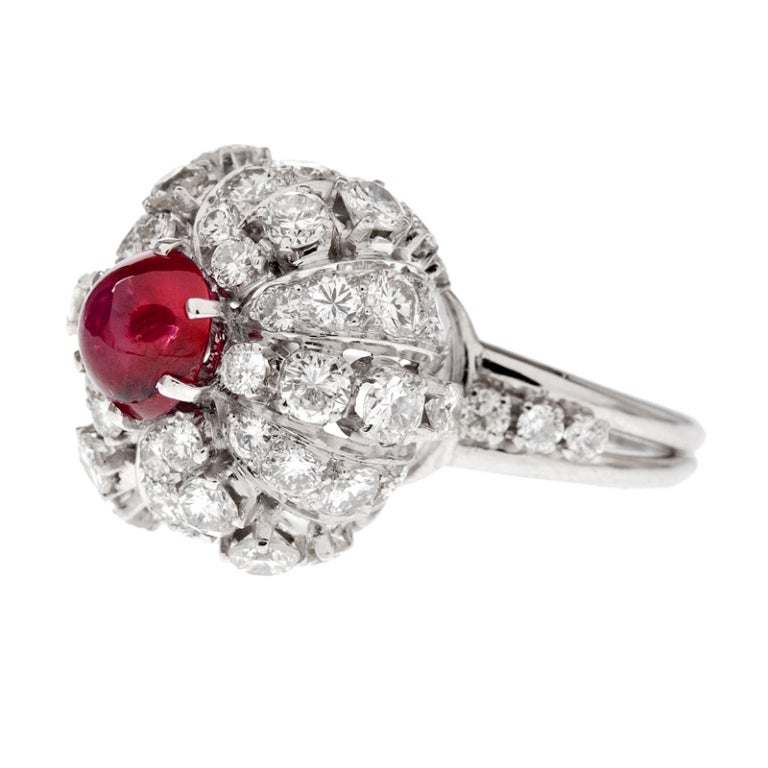 Both chic and unique, a vibrant ruby with a strong star phenomena perches atop a platinum and diamond cluster ring. Pertaining to fine jewelry it is difficult to design and create a piece unlike anything preceding it, however, this designer