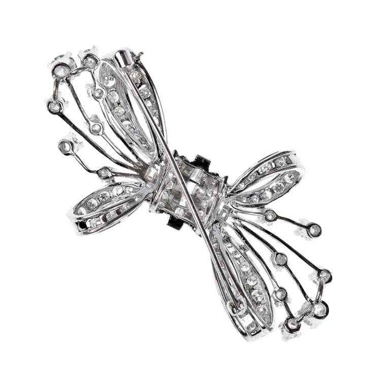 Approximately three carats of diamonds, in round and baguette cuts, create this whimsical bow design brooch.  Measuring approximately 2 - 1/4 inches across by 1 - 1/8 inches in height this lovely piece can be worn in many ways to add sparkle to any