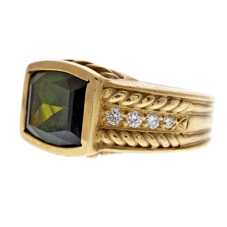 Weighty and bold, this contemporary, signed designer ring is substantial both in design and in its conception. The center stone is an approximately 6 carat fancy cut natural peridot with rich, intense color. Diamonds and a braided gold design sweep