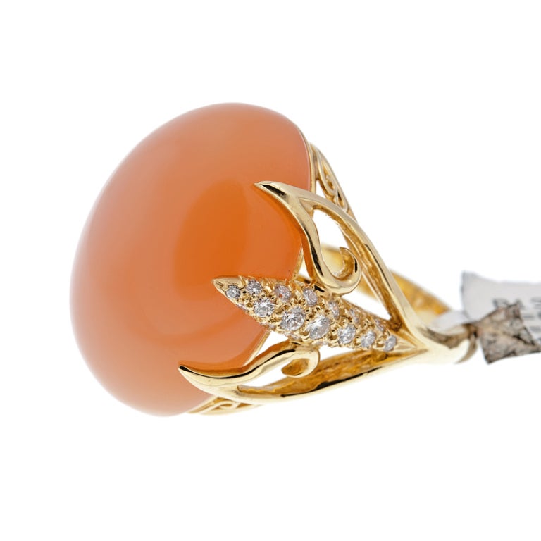 A 36.23 carat natural cabochon cut tangerine moonstone is the star of this stunning ring. Although rather impressive in size, the ring is beautifully contoured to the shape of the finger and the soft, peachy hue of the stone is soothing and