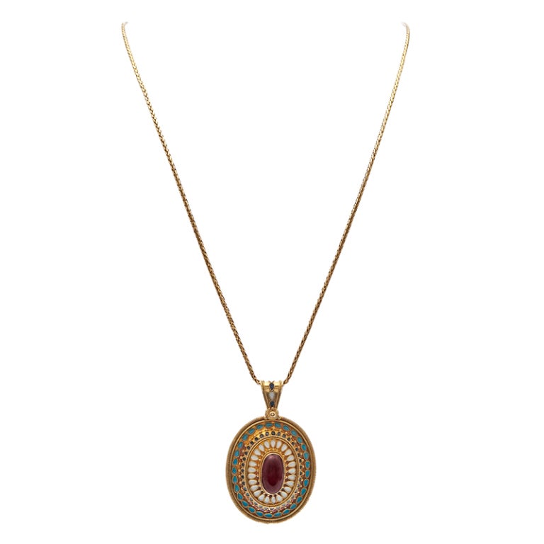 The closer you look, the better it gets! Layers of meticulous combine to create a striking masterpiece of modest proportions.

An oval cabochon garnet framed in a halo of granulated gold begin the story, white enamel petals with a twisted surround