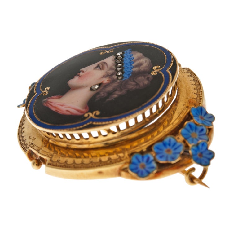 Extremely finely detailed enamel portrait of the profile of a lady, set in 18k yellow gold. Three dimensional blue enamel flowers burst from the sides. Detailed engraving finishes the edges. The enamel is absolutely pristine and is of truly the
