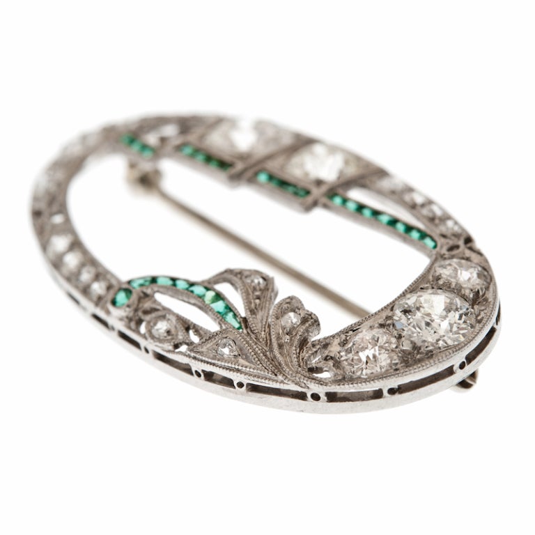 Just the right size for day or evening, this unique oval brooch is hand made in platinum, with approximately 4 carats of old European cut diamonds. A lovely marriage of geometric art deco, with round stones set in square bezels, softened with