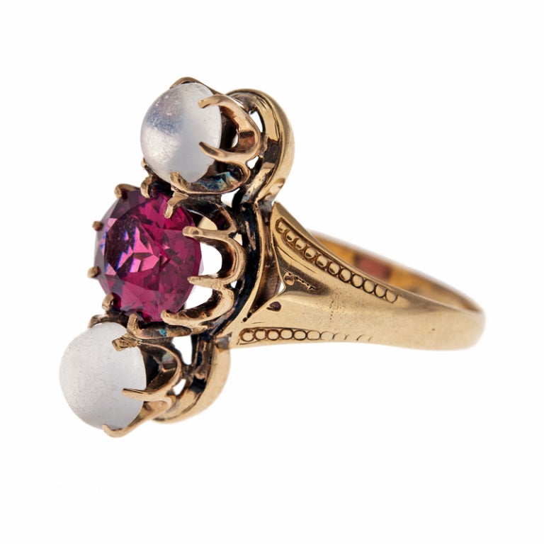 Stunning combination of intense magenta rhodolite garnet and soft cabochon moonstones. The moonstones have a mystical quality which highlights the liveliness exhibited by the garnet. Set in a 14 karat rose gold mounting with detail tapering down the