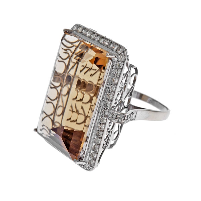 Absolutely giant citrine of 50 carats set in a hand made 18k white gold mounting with a beautiful filigree under gallery and surrounded by a row of 65 diamonds which weigh approximately .75 carats. 

Despite its assertive size, the ring is