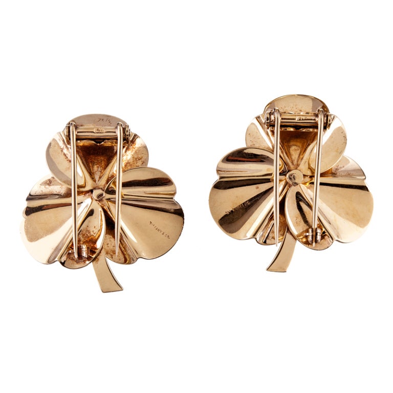 A lovely retro suite by famed design house Tiffany & Co. Created in the form of a flower, this suite is made up of two double-clips and a pair of matching earrings. A small pop of blue adds a nice touch in conjunction with the warm rose gold tone. 