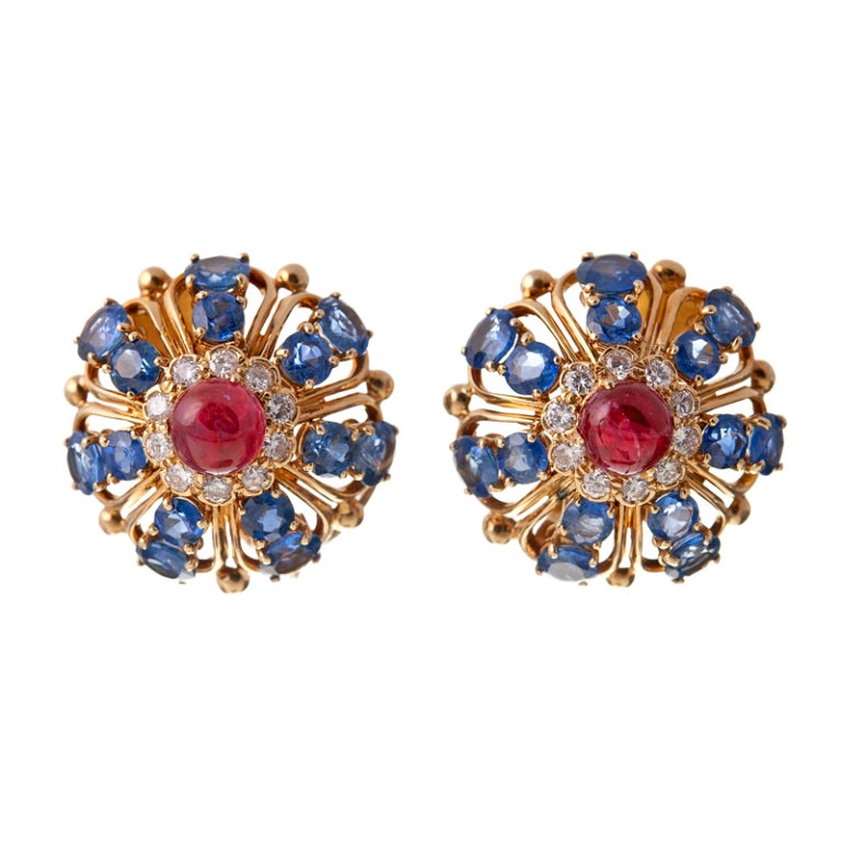 Unbelievable style and a dazzling display of the finest gemstones: A pinwheel design on top of sapphires, diamonds and cabochon rubies and stunning compliment with polished golden wire work. The bottoms, a detachable enhancer of gleaming emeralds,