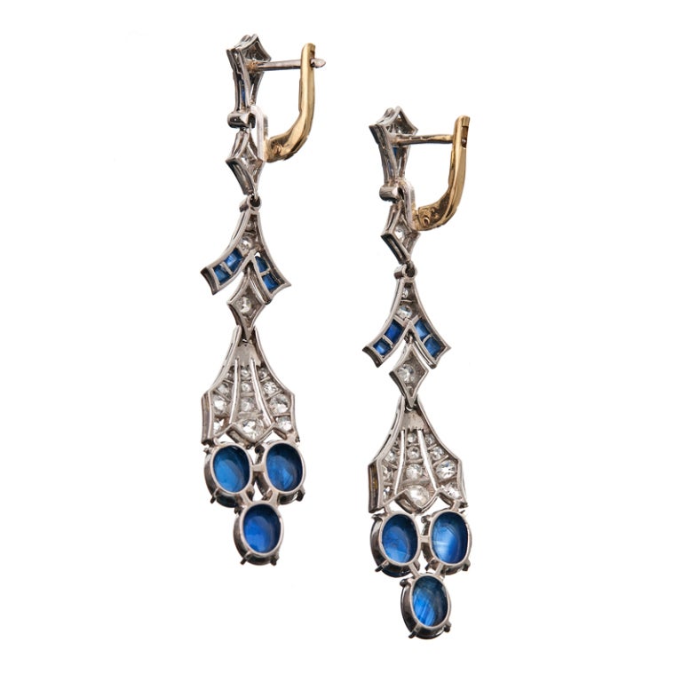 Meticulous art deco detail at its finest: clusters of cabochon sapphires nestled at the bottom of a classic art deco design. Sweeping segments of diamond-studded platinum, sharp angles fitted together with masterful skill... 

The earrings have
