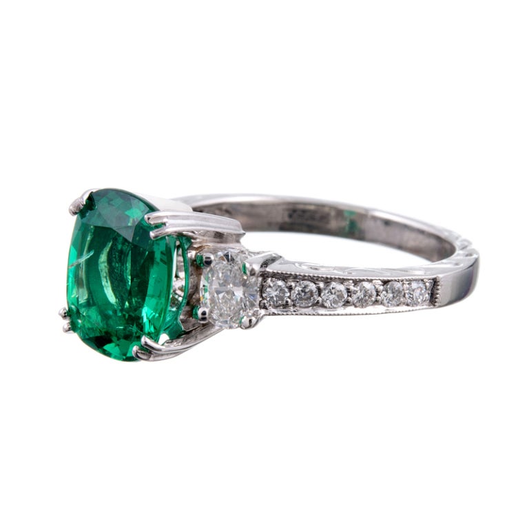 A lovely emerald ring in a fine platinum mounting with just enough diamonds to make this ring look important without overshadowing the major center stone. A pleasant balance is struck with an oval emerald, flanked by oval diamonds- a welcome