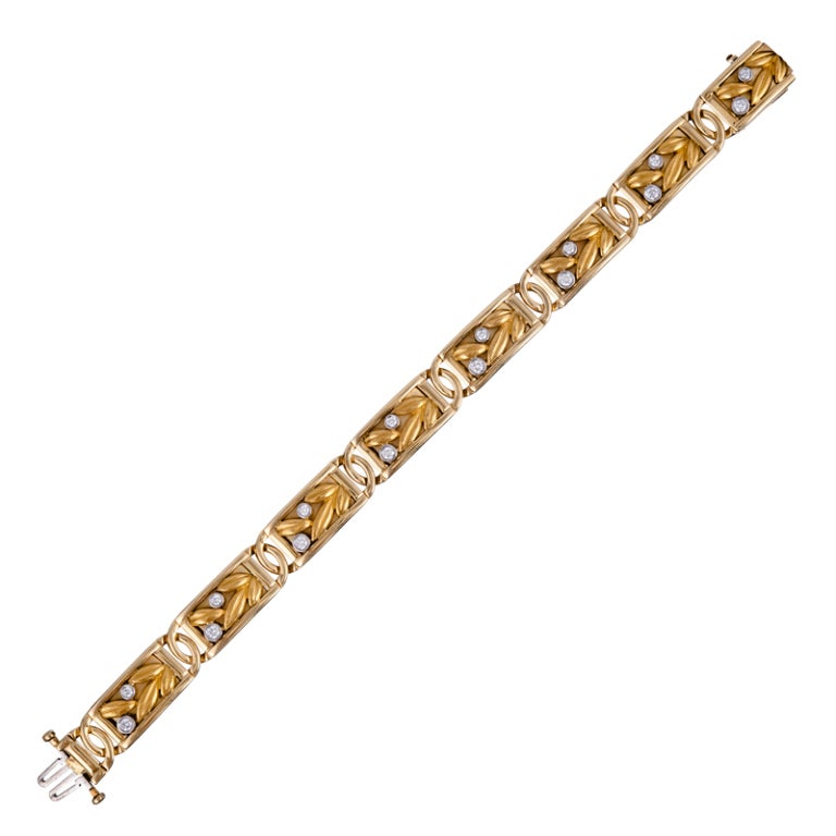 Designed as a series of eight rectangular links decorated with three-dimensional golden leaves and bezel set diamonds, this bracelet is clearly inspired by the feminine and organic details which make art nouveau jewelry so distinctive, yet it has
