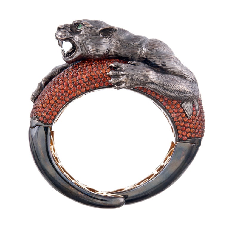 This bold expression of craftsmanship is a testament to the talent of this artist. 18k yellow gold with black rhodium and a gorgeous scrolling under gallery, the bracelet opens with a hinge on either side and is decorated with intense orange