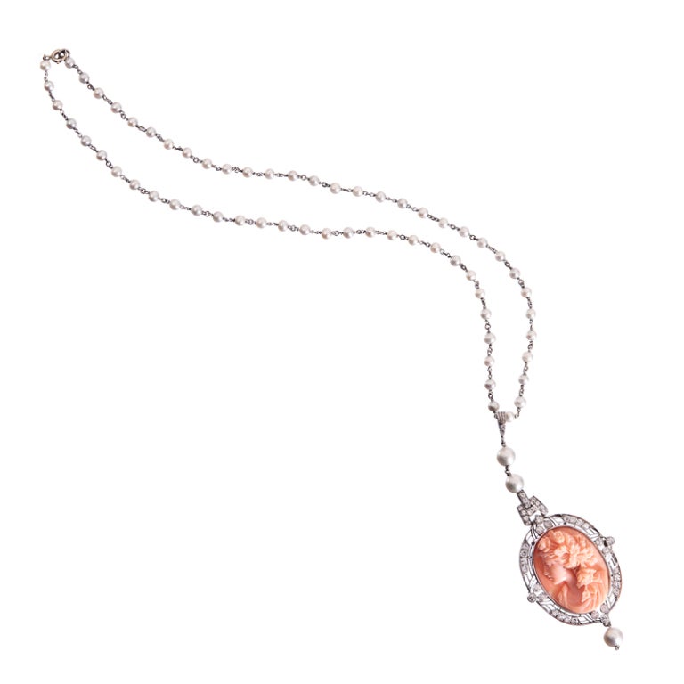 Achieving a lovely balance between art deco and art nouveau, this stunning and feminine necklace is abundant with lifelike detail. The pretty coral cameo is framed in a hand made 18K white gold art deco style bezel, decorated with diamonds and