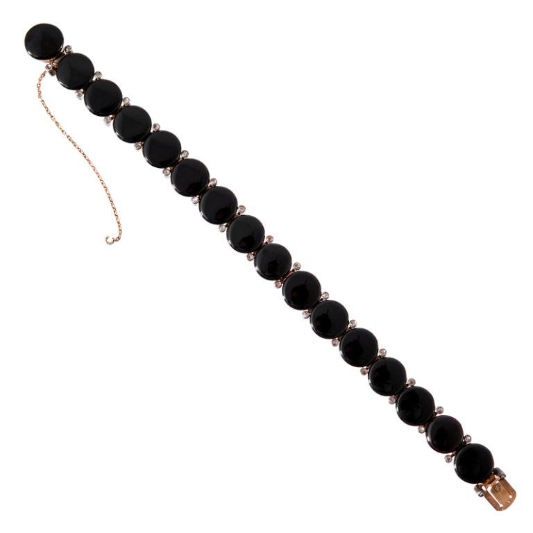 Bracelet crafted of rose gold plate over silver and designed as a line of raised onyx discs with bezel-set rose cut diamonds spaced between. Bold styling, particularly for an antique piece. 
7.25 inches long,