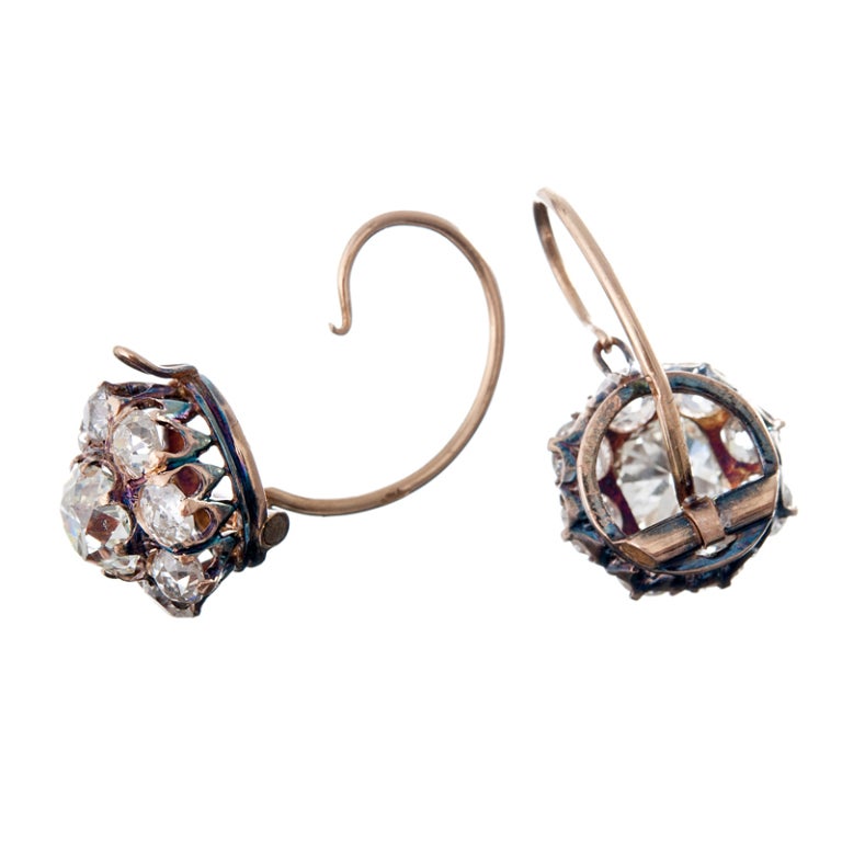 18k rose gold with a 1.25 carat old European cushion cut diamond in the center of each earring. The surrounding old European cut diamonds weigh an additional 1.50 carats per ear. These are magnificent antique earrings, finished with an ear wire