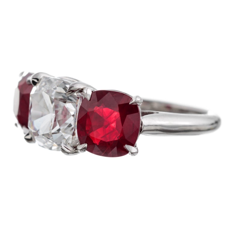 An uncommonly magnificent rendition of this celebrated style: The center diamond, deserving of note on its own, is a 3.01 carat cushion cut with a GIA grade of G color, Vs2 clarity. It is flanked by a pair of ideally matched rubies. The rubies are