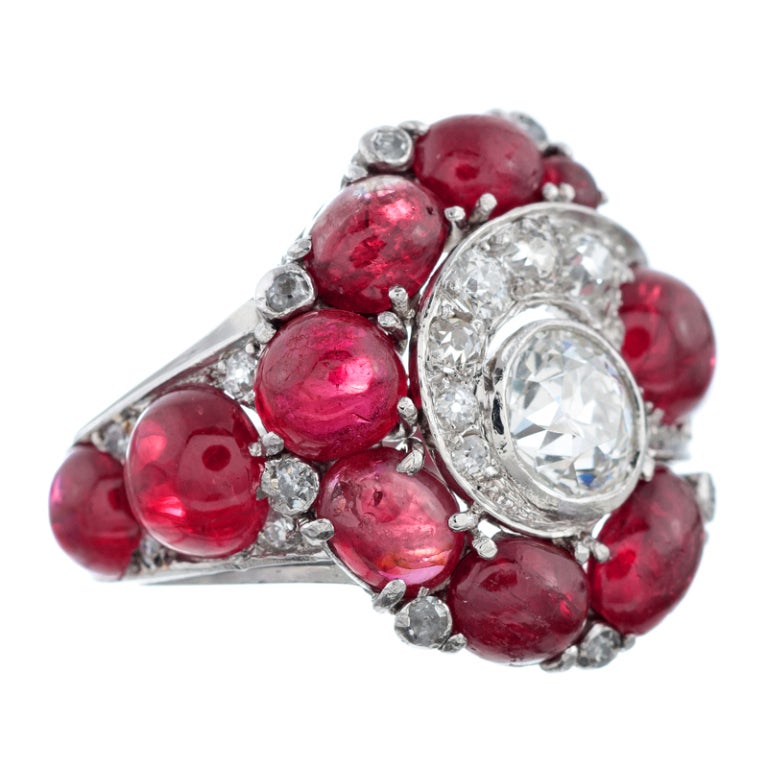 Marrying art deco and retro design in artful splendor, this ring makes a bold statement with its combination of cabochon rubies and brilliant diamonds. The bezel set diamond in the center weighs .88 carats, with an additional .40 carats of accent