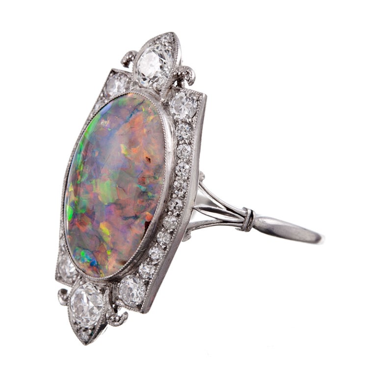 Outstanding art deco plaque ring, with an approximately 4 carat black opal, enhanced by a stylized frame of 1 carat of diamonds, set in platinum. Classic art deco detail, with fleur-de-lys shaped finials, millegrain and superior craftsmanship, this