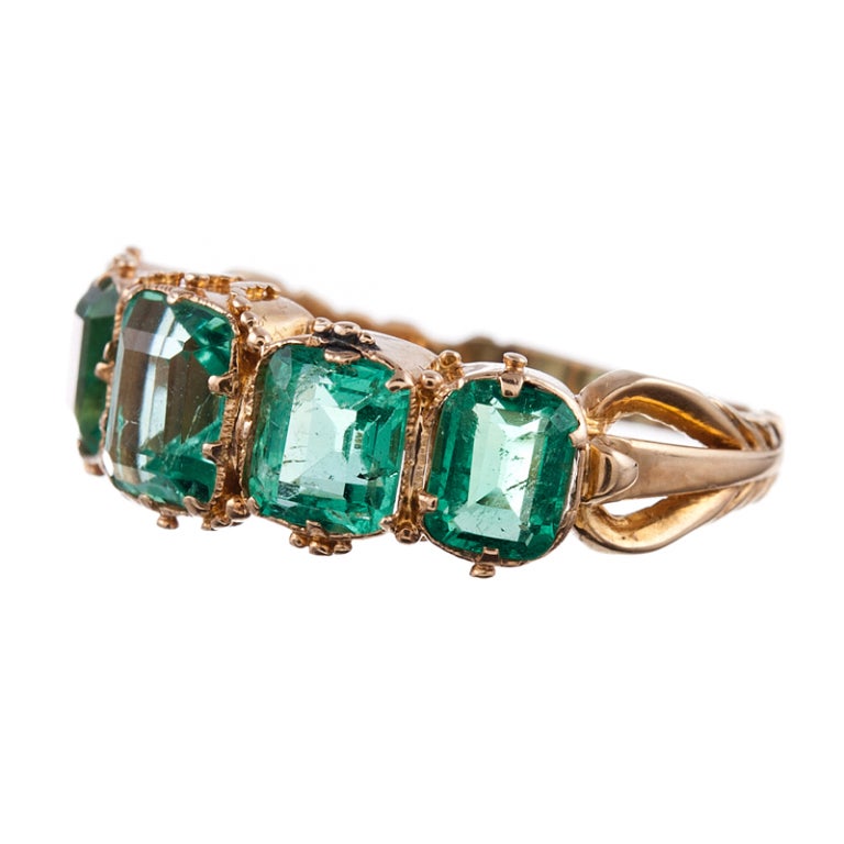 A fine example of this celebrated and eternally beloved classic, with five emerald cut emeralds set in 18k yellow gold and finished with detailed shoulders. The emeralds weigh approximately 2.20 carats in total and are well=protected in this