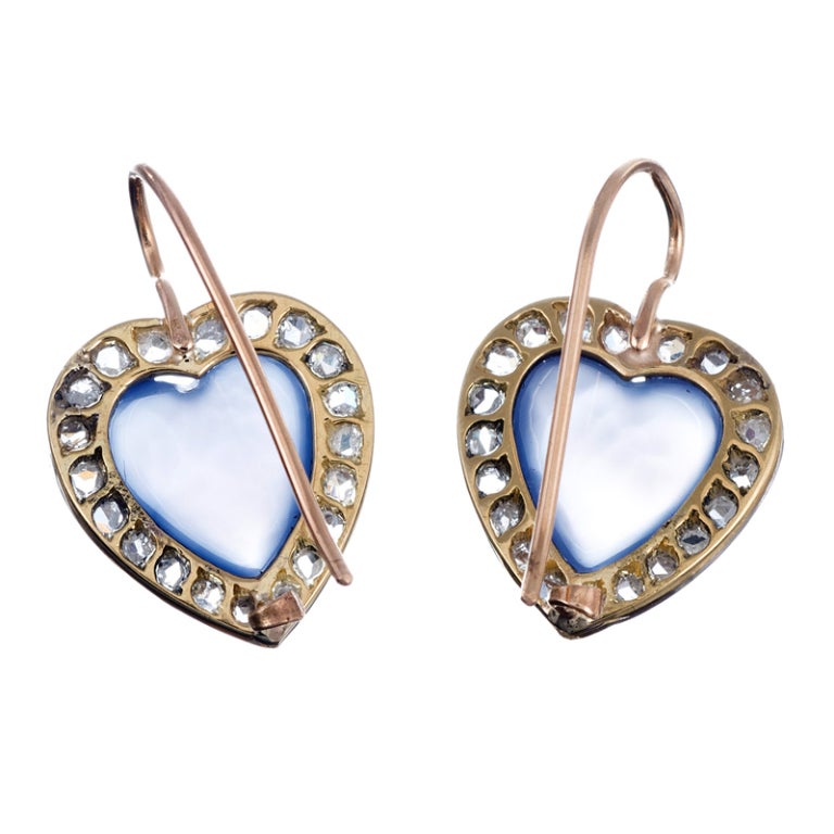 Platinum earrings backed in 14K yellow gold; a charming heart design, an ever-enduring symbol of devotion, carved of calcedony and framed in rose cut diamonds. The center stones have a subtle, mystical allure, which is brightened by the flash of the