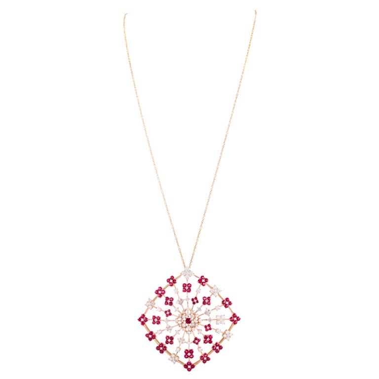 New old stock Salavetti pendant consisting of a rather large sideways square suspended from a 28 inch yellow gold chain.

The pendant measures 2.5 inches in tip-to-tip diameter and is a brilliant display of bursts of ruby- and diamond flowers. The