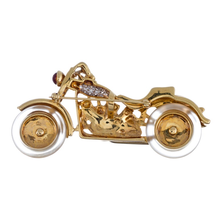 Truly superior craftsmanship and attention to detail with this playfully-themed brooch. 18k yellow gold, with a diamond gas tank, mother of pearl seat, fenders and saddlebags and rock crystal tires which are articulated to spin around like the real