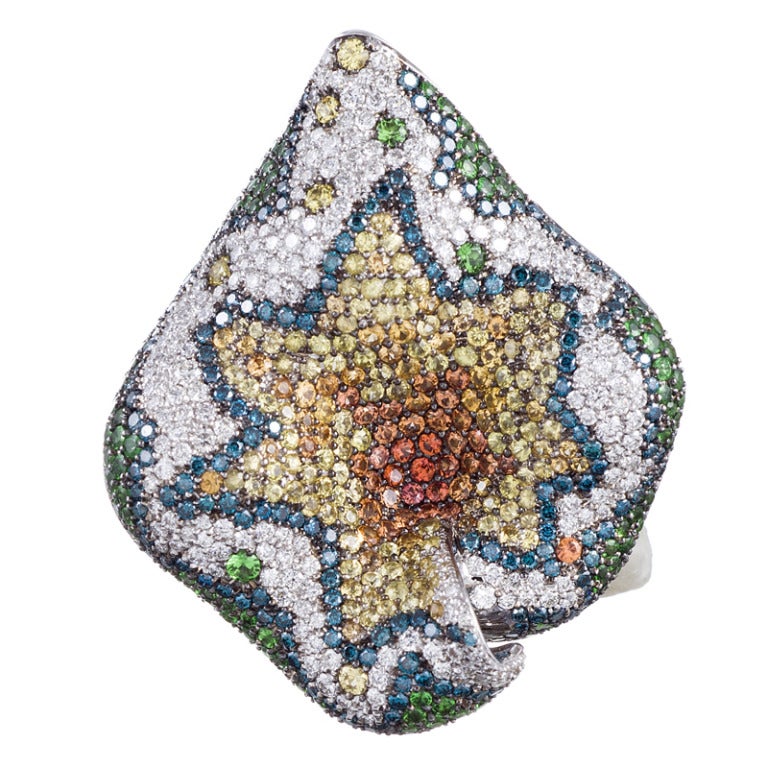 Two piece set of a large ring and pendant with a three-dimensional leaf motif, absolutely encrusted in diamonds and gemstones. The ring ring measures 1.25 by 1.5 inches from the top and rises modestly off the finger. The pendant measures 2 by 1.75