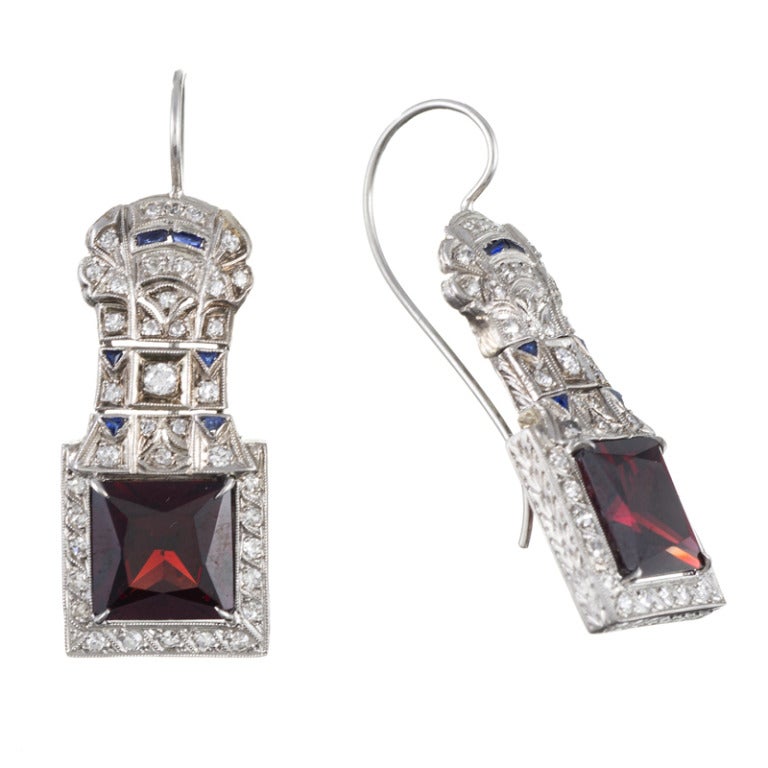 Platinum drop earrings, original art deco, circa 1920s, with 6 carat each square garnets, complimented by a peppering of diamonds and sapphires. This creates a distinctive, yet subtle, red, white and blue theme. The earrings measure 1.75 inches in