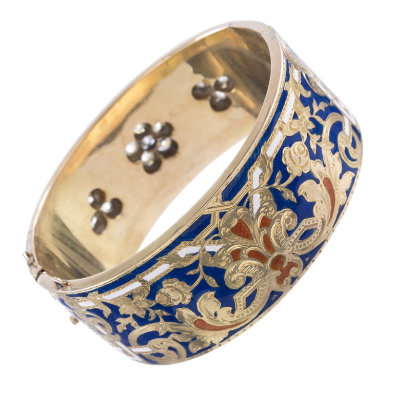 18k yellow gold cuff, single hinge with blue-, white and orange enamel on one side and a trio of diamond clusters set on a backdrop of blue enamel on the other. Gorgeous, intricate scrolling designs with detailed engraving add extra dimension. There