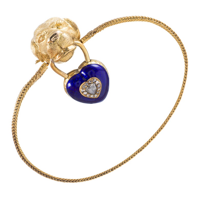 15k yellow gold bracelet with the sculpted head of a dog at the center. Suspended from his mouth is a blue enamel heart-shaped locket, set with rose cut diamonds. This is a sweet and playful motif and an all-around charming bracelet.