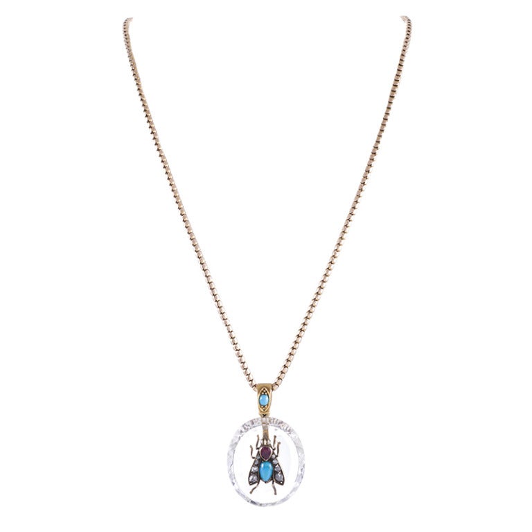 A transparent canvas of rock crystal, faceted on the sides, provides the backdrop for this traditional Victorian theme. Crafted of 15 carat yellow gold and decorated with turquoise, diamonds and a ruby, this is playful and unusual piece to add to