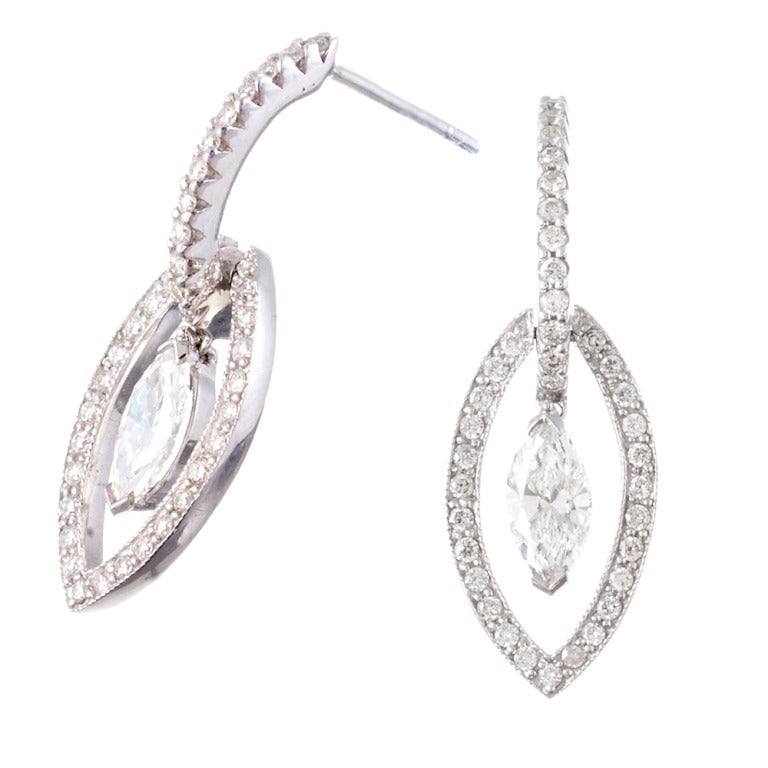 14k white gold earrings consisting of a teardrop-shaped and diamond-studded open frame suspended from a half hoop and decorated with a marquis brilliant diamond at the center. These earrings have a subtle, feminine impact and movement, allowing the
