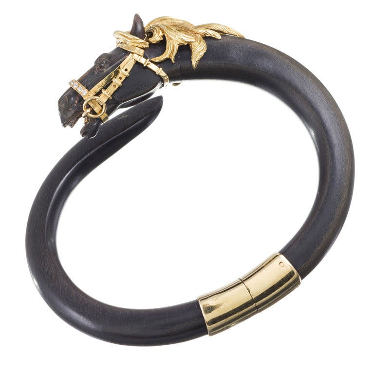 Super chic vintage styling with an expertly carved horse's head, complimented by a finely detailed golden mane and bridle. This bracelet is made of ebony and cannot be resized. Internal diameter of 2.5 by 1.75 inches, finished with a single 