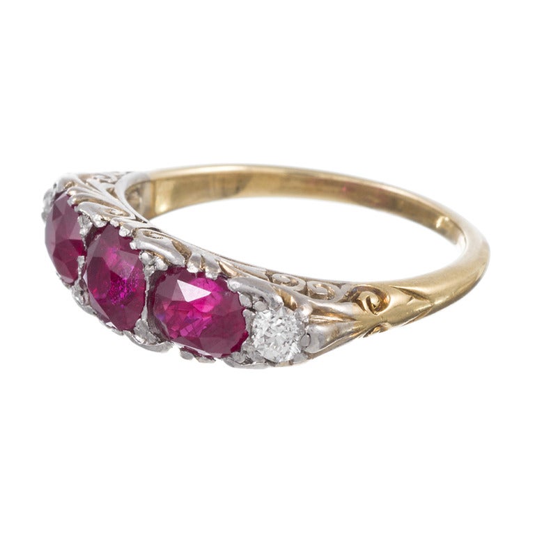 Platinum and yellow gold, classic carved ring with 1.55 carats of rubies and .20 carats of diamonds. The rubies exhibit all the properties of Burma rubies and are rich with color and vibrance. This ring can be resized on request.