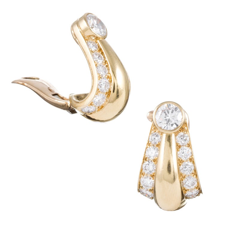 A stylized variation of a classic style, these Cartier earrings are set with a .75 carat round diamond atop each ear and further decorated with a sweeping row of diamonds on either side of the raised drop center. In total, 3.30 carats of diamonds