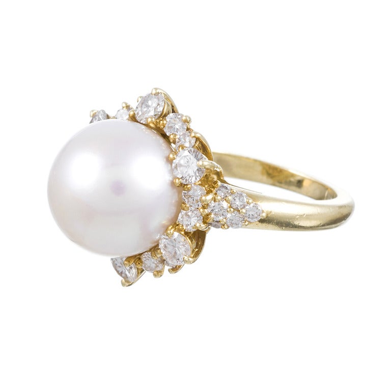 18k yellow gold ring with a 12.5 millimeter white pearl center and 2 carats of round diamonds dancing about its circumference. Resizable on request.