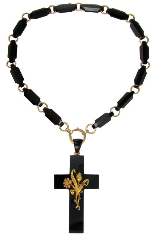 Graceful leaves and flowers, hand chased in 14 karat yellow and rose gold, adorn the center of the cross. The bale is enamel over gold. The bale connects to the circular clasp enabeing the cross and the link chain to lay perfectly flat.<br />
Link