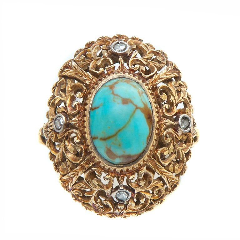 A master jeweler's delight, this 18K Yellow Gold Edwardian Turquoise Ring is hand pierced and hand chased. The bezel that wraps the turquoise and the shank are hand engraved. The design includes four bezel-set, also hand engraved, rose cut diamonds.