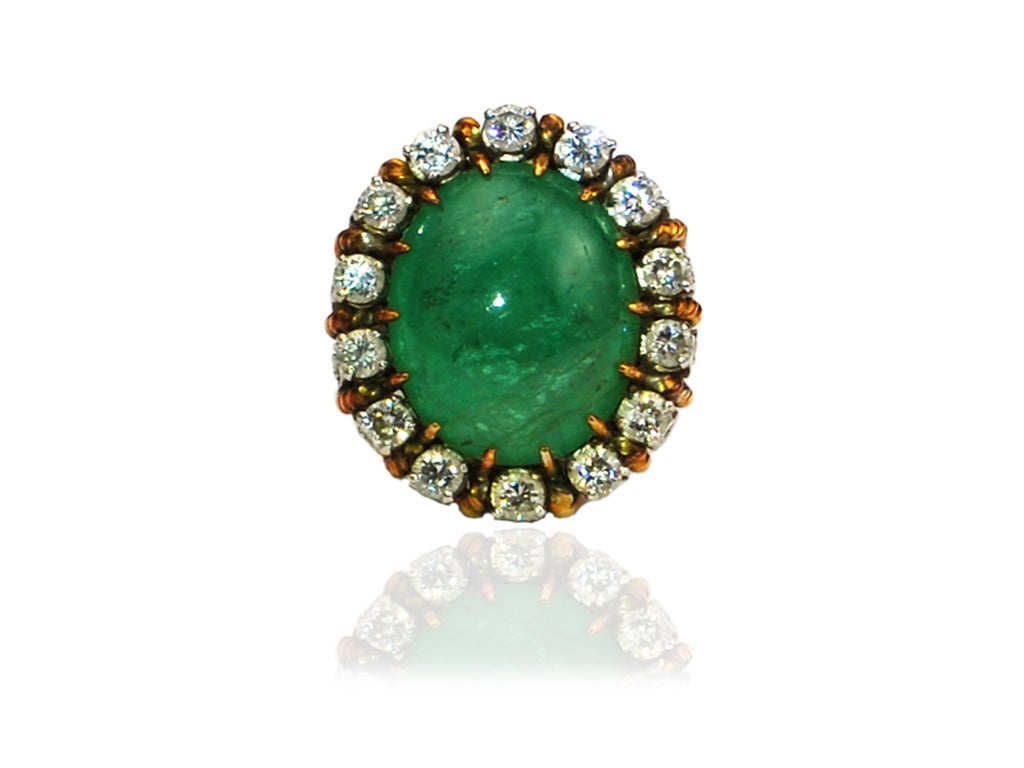 This state of the art ring with an approx. 12 ct Colombian Emerald cabochon center and approx. 5 1/4 cts of Diamonds surrounding it is set in Platinum and Yellow Gold. The decorative ring shank features diamonds and gold metal cable-like twists in