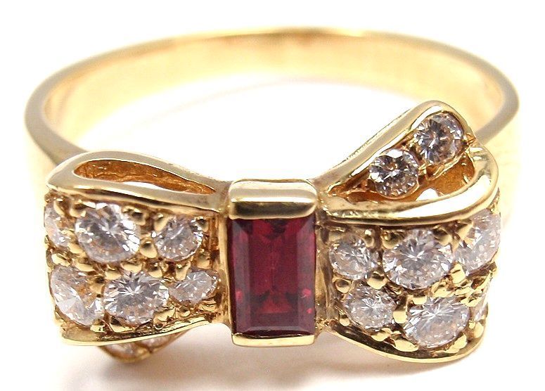 18k Yellow Gold Diamond & Ruby Bow Motif Ring by Van Cleef & Arpels. With 16 round brilliant cut diamonds, VVS clarity, F color. Total Diamond Weight: .48CT. And 1 Ruby stone: 5mm x 4mm. 

Details:
Weight: 3.4 grams
Ring Size: 5.5 
Width: