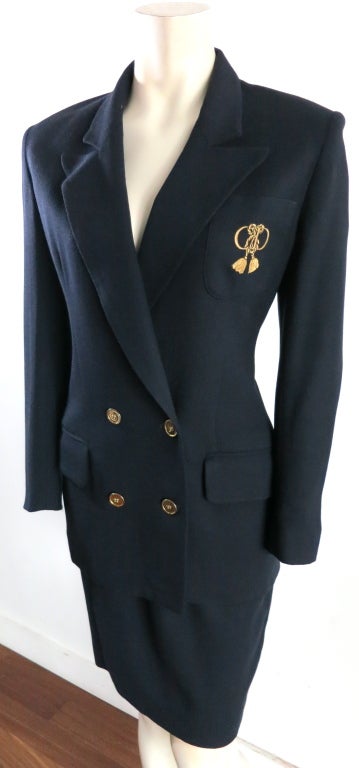 Christian Dior 1980's era dark navy blue, pure wool suit with left chest metallic gold, tassel style, logo embroidery.  Double breasted front closures with polished gold button closures.  Peaked front lapel shape.  Dual waist level flap pockets. 