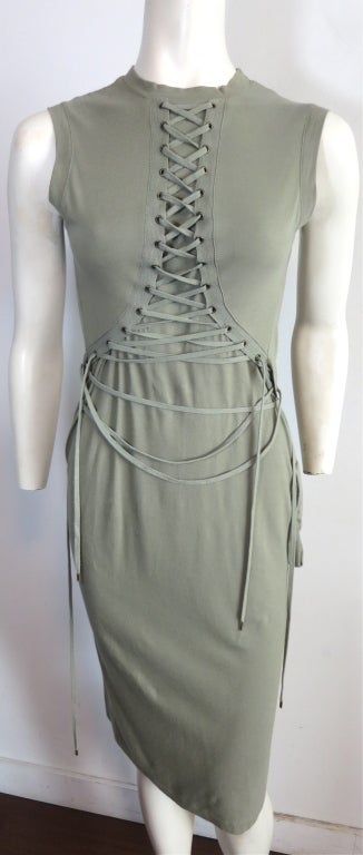 Christian Dior green knit jersey tank dress with extreme lacing detail from front to back.  The lacing detail is intended to have an exaggerated, unlaced look which tapers up to the front neck from the rear back panels.  Cargo style pocket detail at