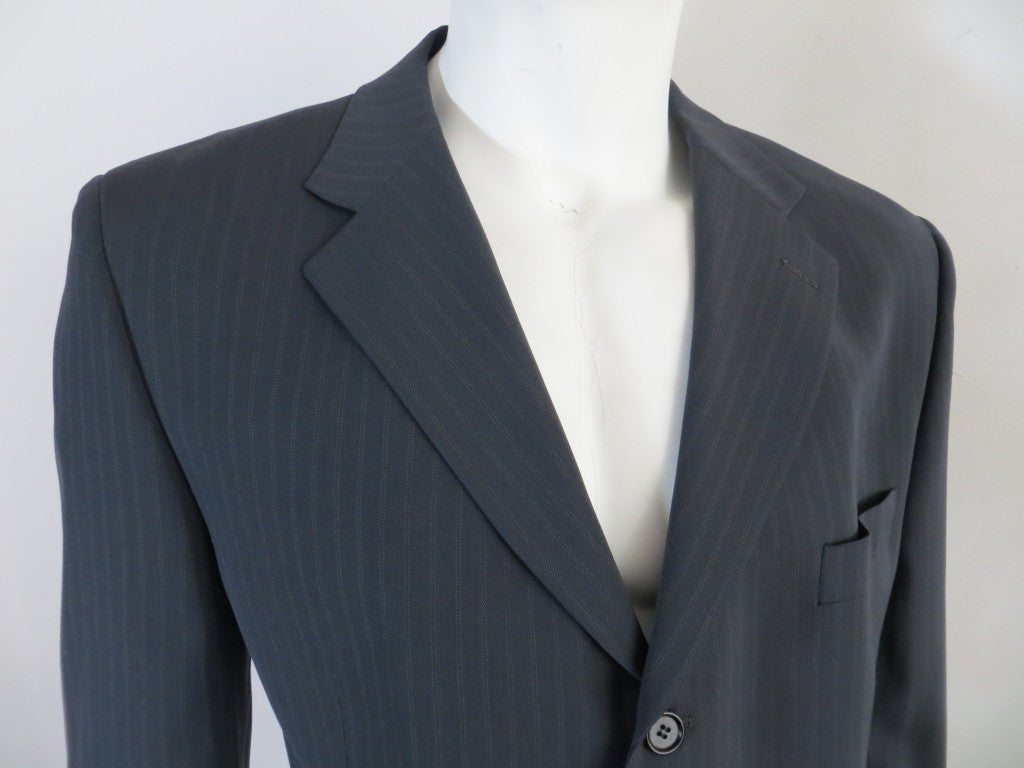 Original ALEXANDER McQUEEN men's 1998 tailored suit jacket in dark gray pinstripe wool.  Triple button front closures with dual waist level flap besom pockets.  Fully lined.  Underarm to underarm: 22